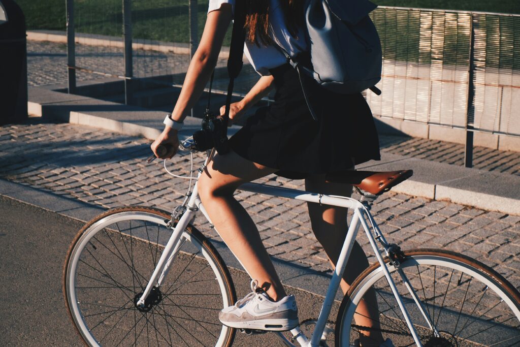 a girl in a black squirt rides a bike down a city sidewalk