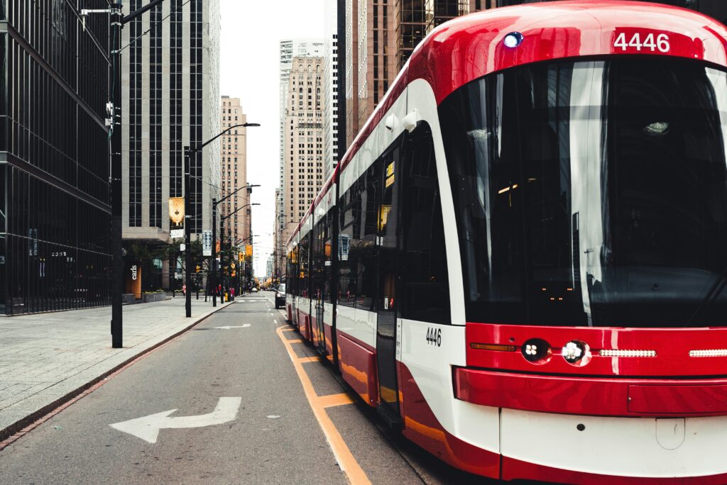 a red bus on the side of a busy city sidewalk, one of the best methods of green transportation 