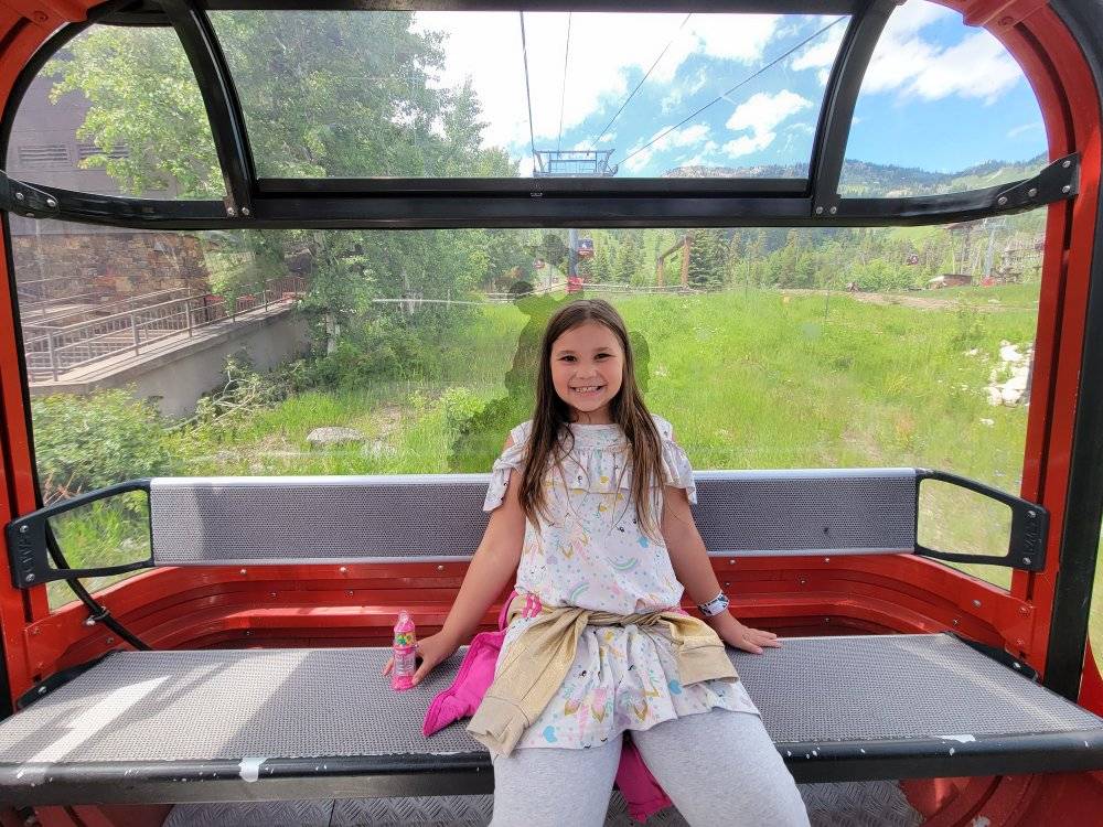 Child riding gondola at Jackson Hole Mountain Resort, enjoying scenic mountain views