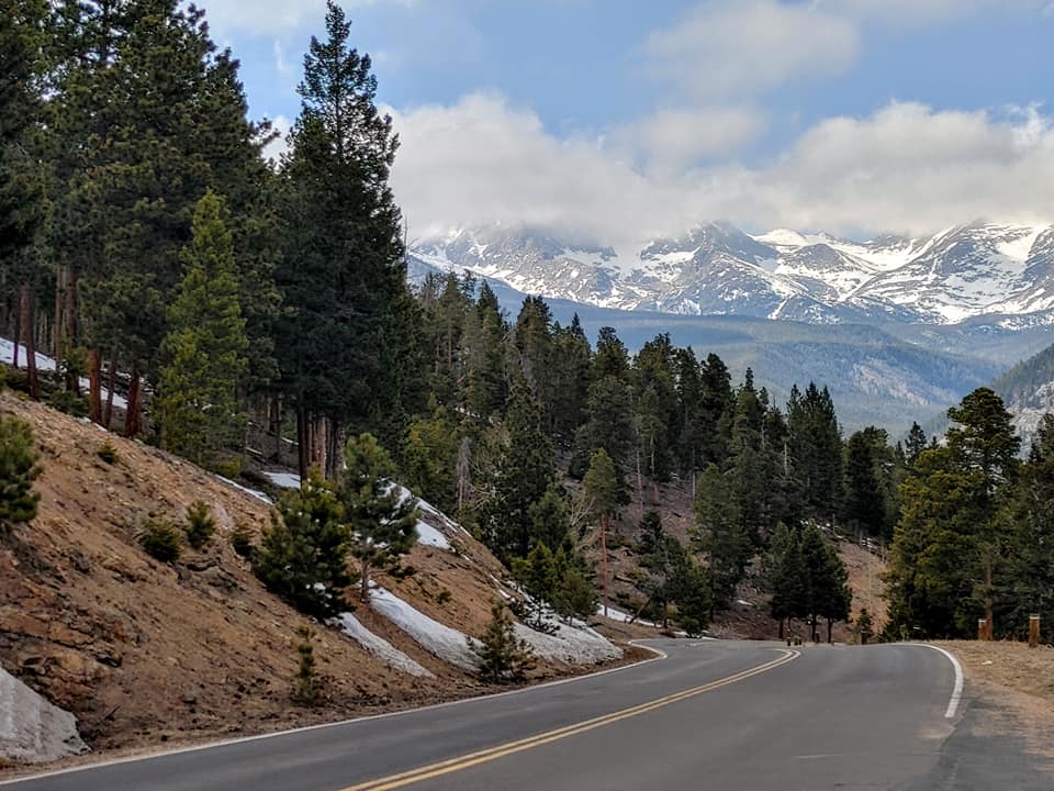 Winding mountain road through the forests and snow-covered peaks of Rocky Mountain National Park.