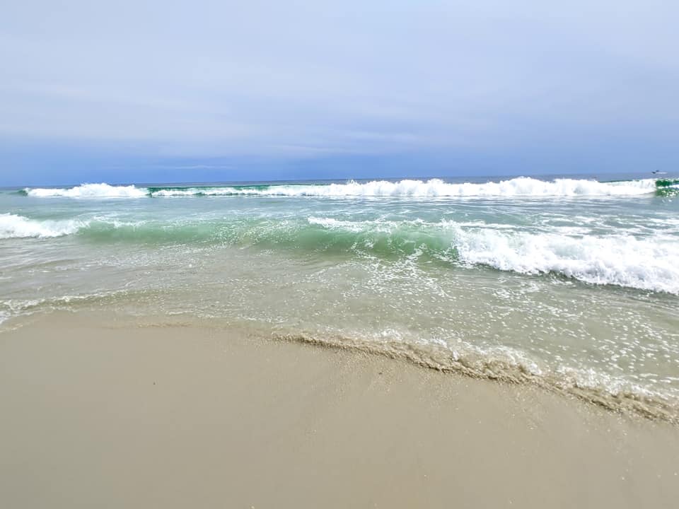 Ocean waves rolling onto the sandy beach at Hither Hills State Park under a blue sky.
