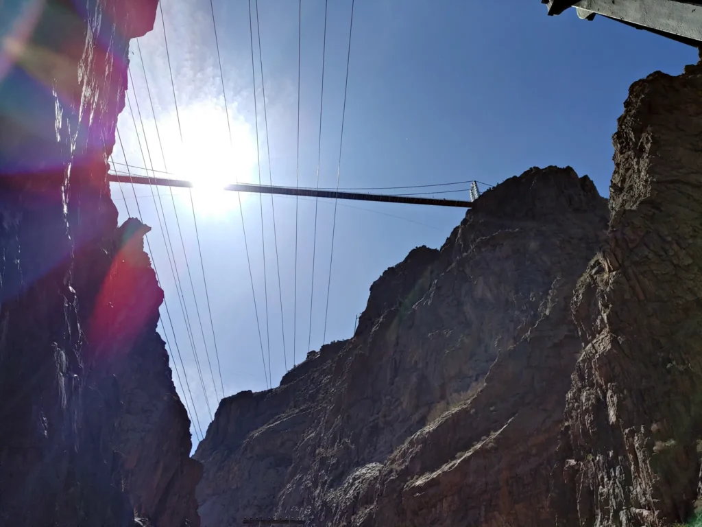 towering canyon walls against a blue sky with the Royal gorge suspension bridge in the distance, one of the main highlights of a visit to Cañon City Colorado