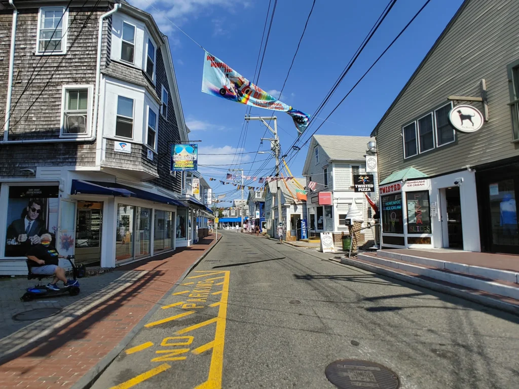 looking down the paved Commercial street of Provincetown with buildings/shops on either side of the street. 