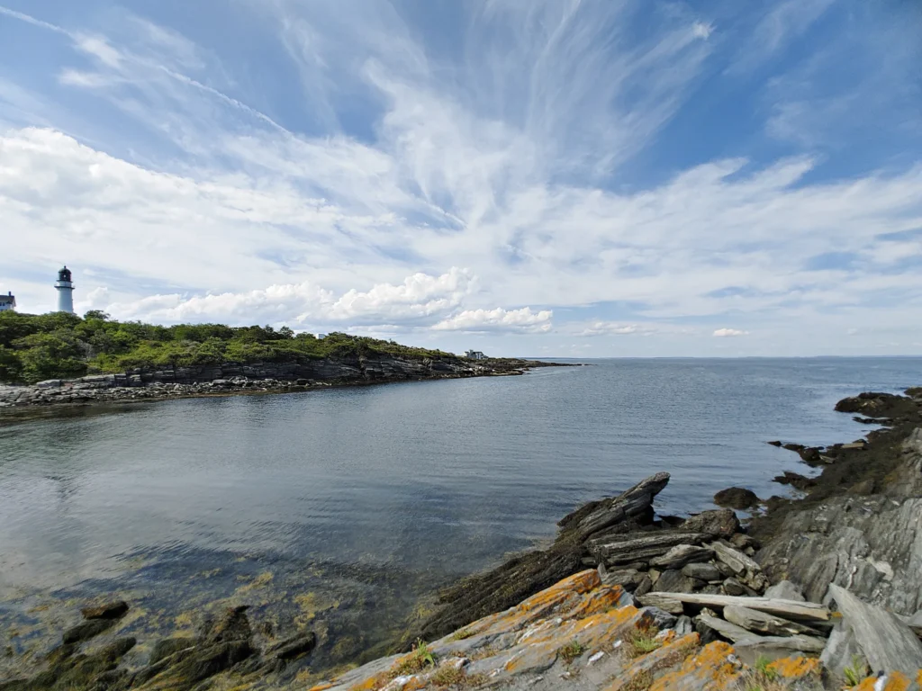 one of the Two white Lighthouses in Two Lights State Park on a rocky coastline with a small body of water in the foreground