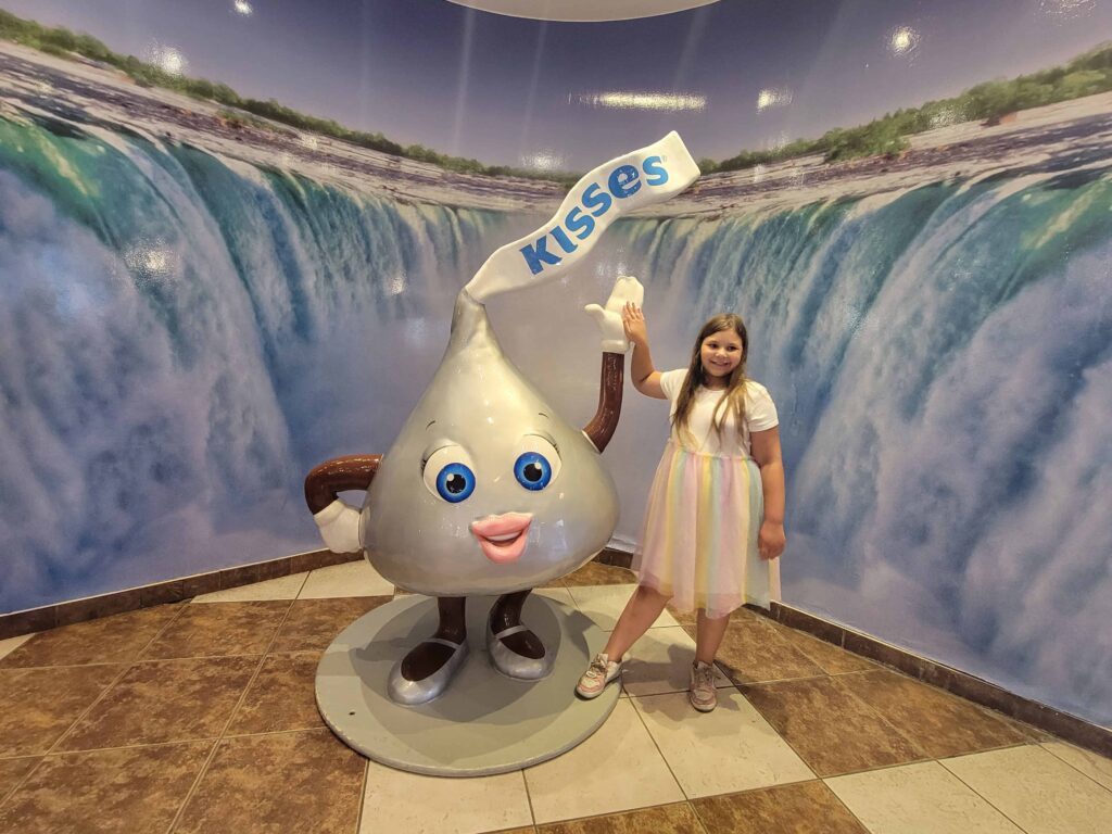 A child poses beside a giant Hershey's Kiss character statue inside Hershey's Chocolate World in Niagara Falls.