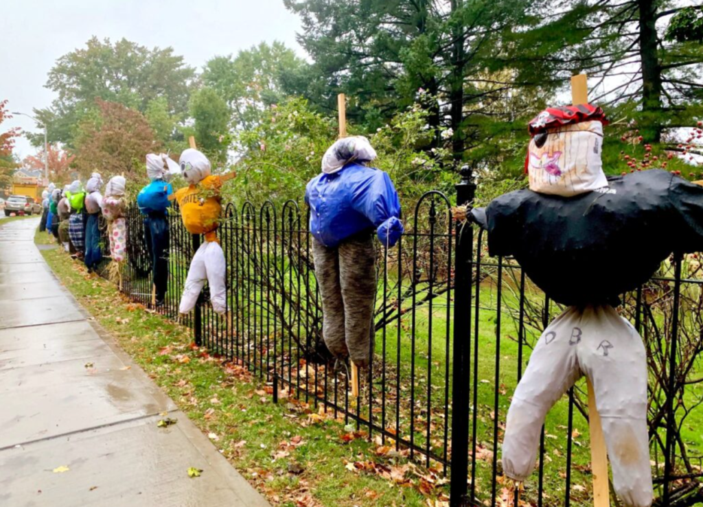 colorful scarecrows lining a black, metal fence