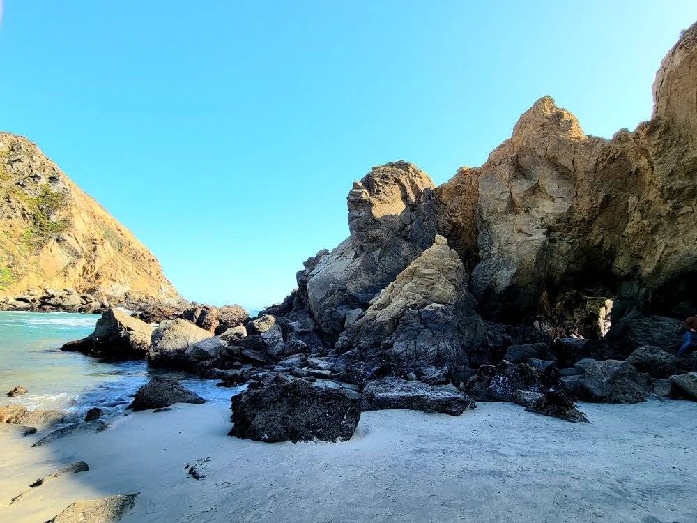 Rocky beach and cliffs along the Big Sur coast with clear blue water.