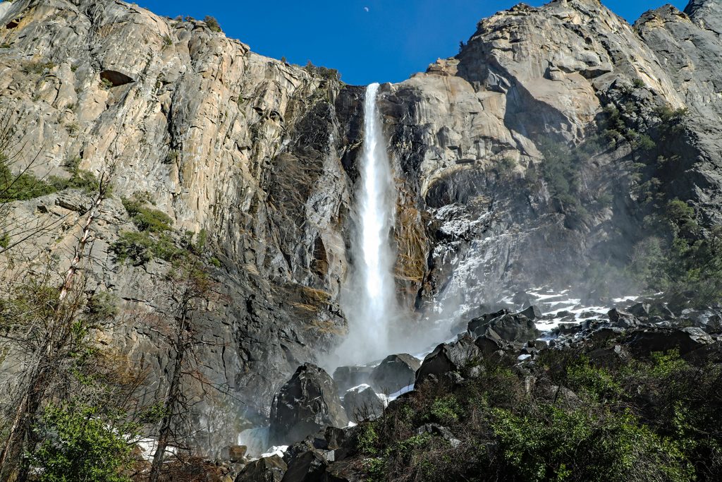 Bridalveil Falls pouring over granite cliffs to a rocky base inside Yosemite National Park