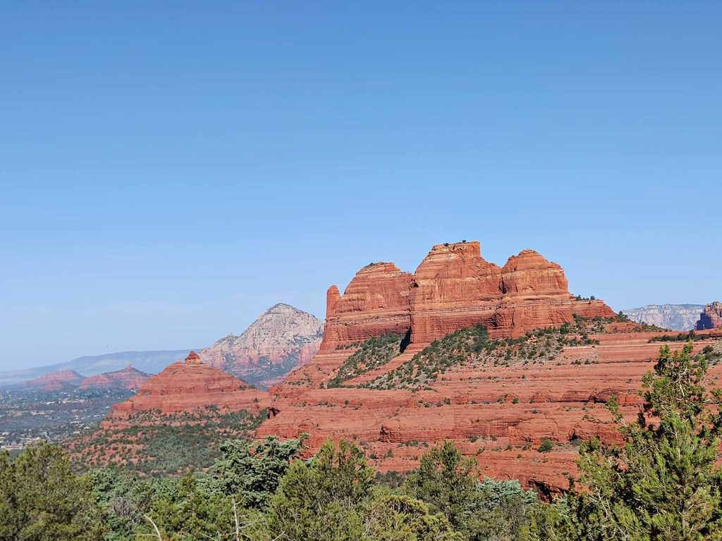 view of the colorful cliffs and red rocks in Sedona Arizona with lush greenery in the foreground 