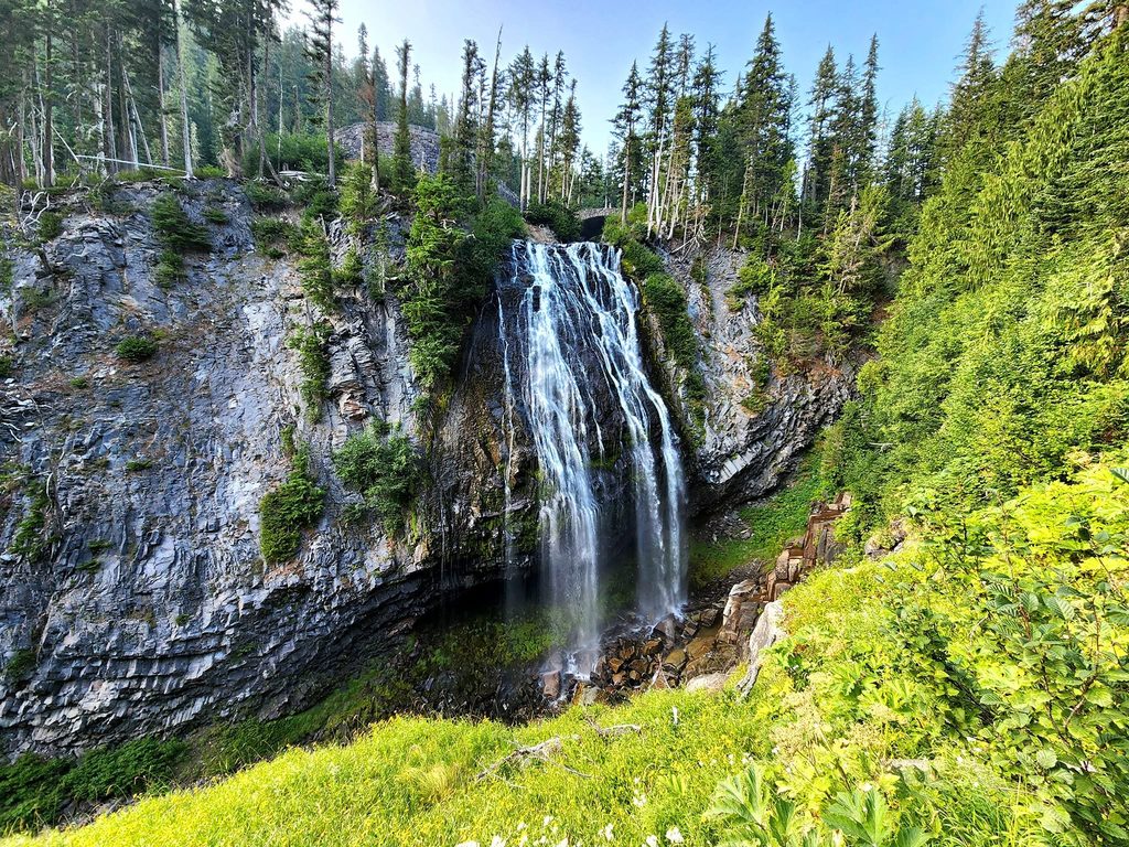 Mount Rainier waterfall surrounded by evergreen forest and rocky cliffs